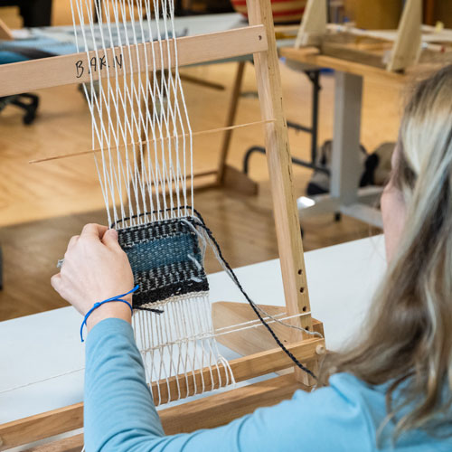 Fiber Arts student working on a small tapestry on a Navajo-style loom