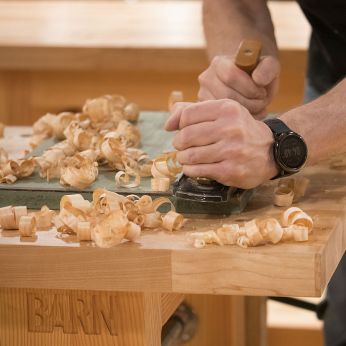 Woodworker using a hand plane in the Woodworking Studio Bench Room