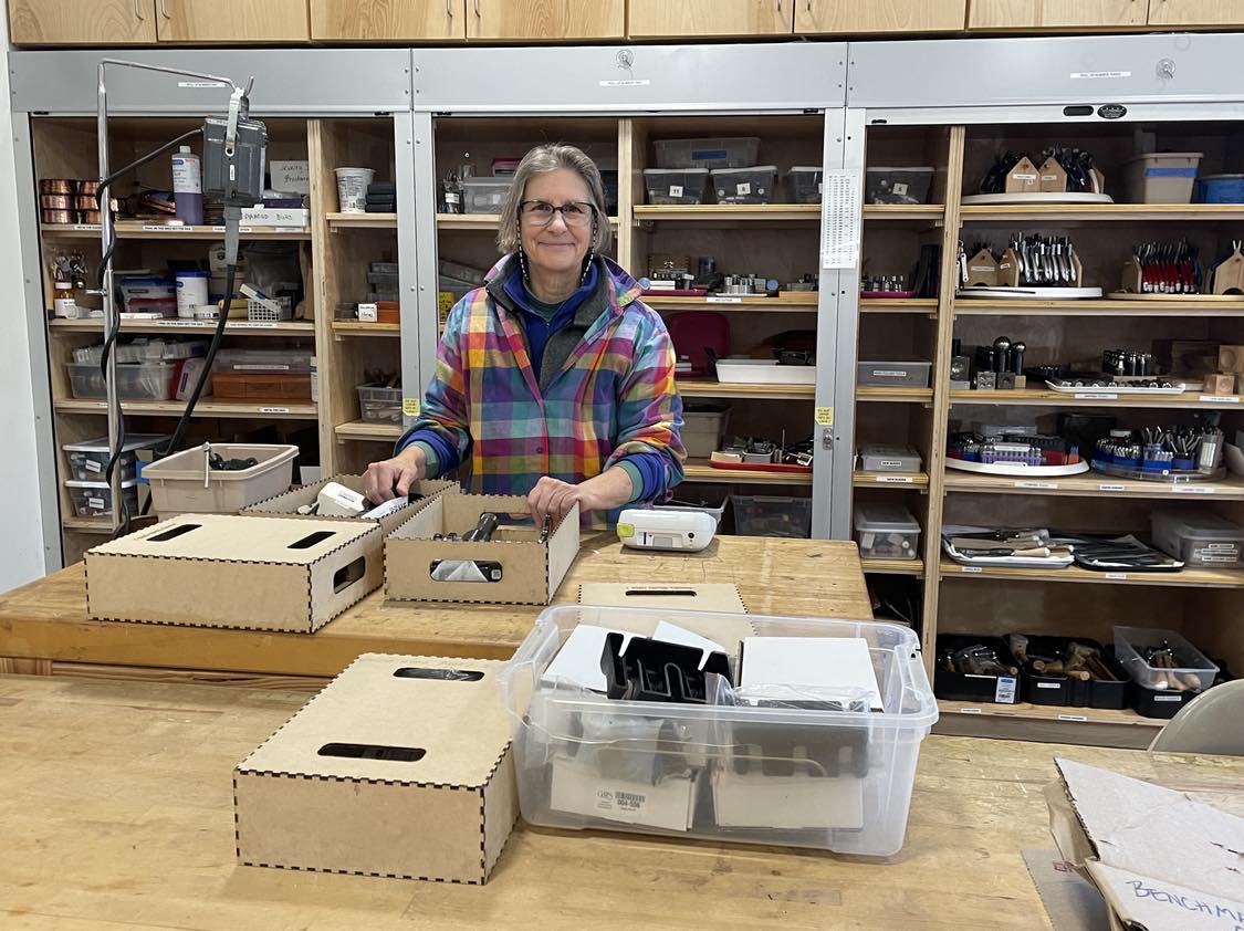 Jewelry Studio Monitor Sue McCarthy with some of the custom boxes she made in the Tech Lab. These boxes are sturdy and stackable and protect sensitive equipment.