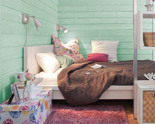 photo of a bed and mint-green finished wood walls.