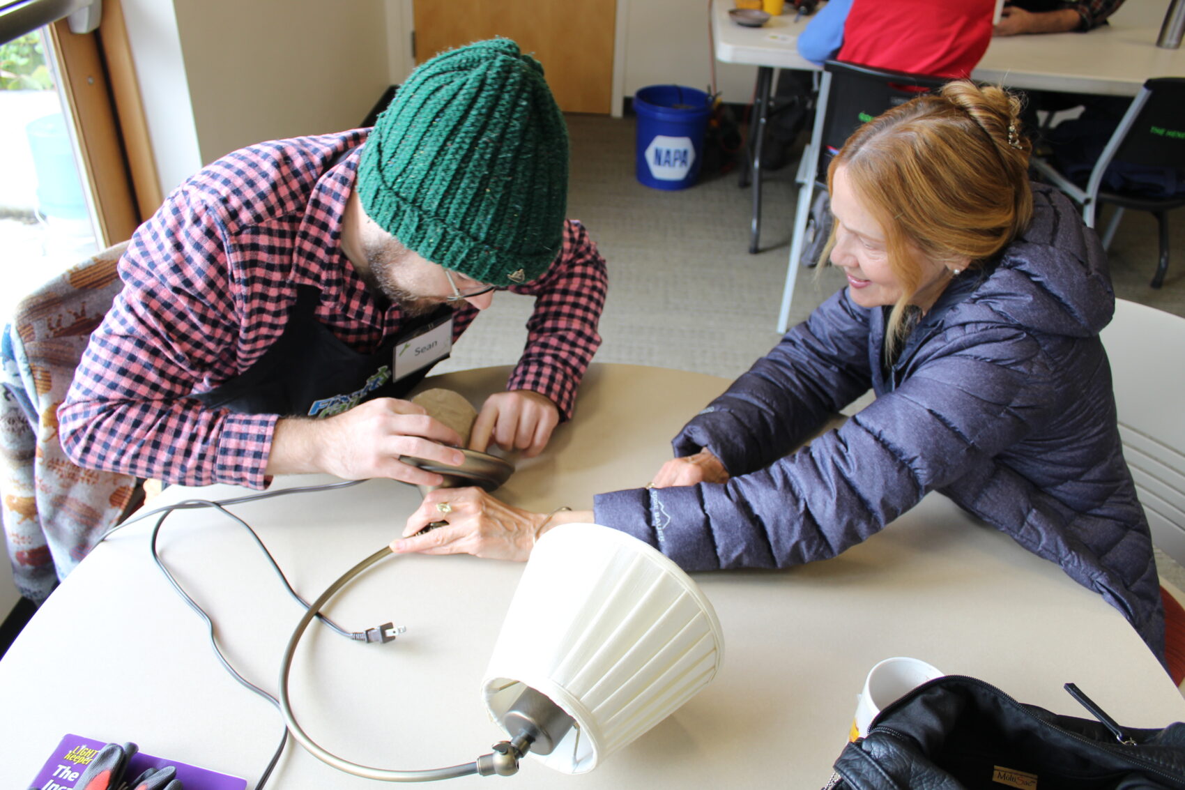 Fixer helps a woman repair a lamp